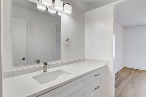 A white bathroom with a sink and mirror.