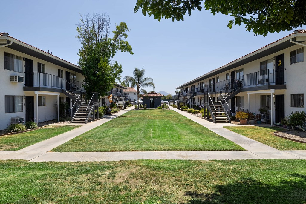 A row of apartment buildings with green lawns in front.