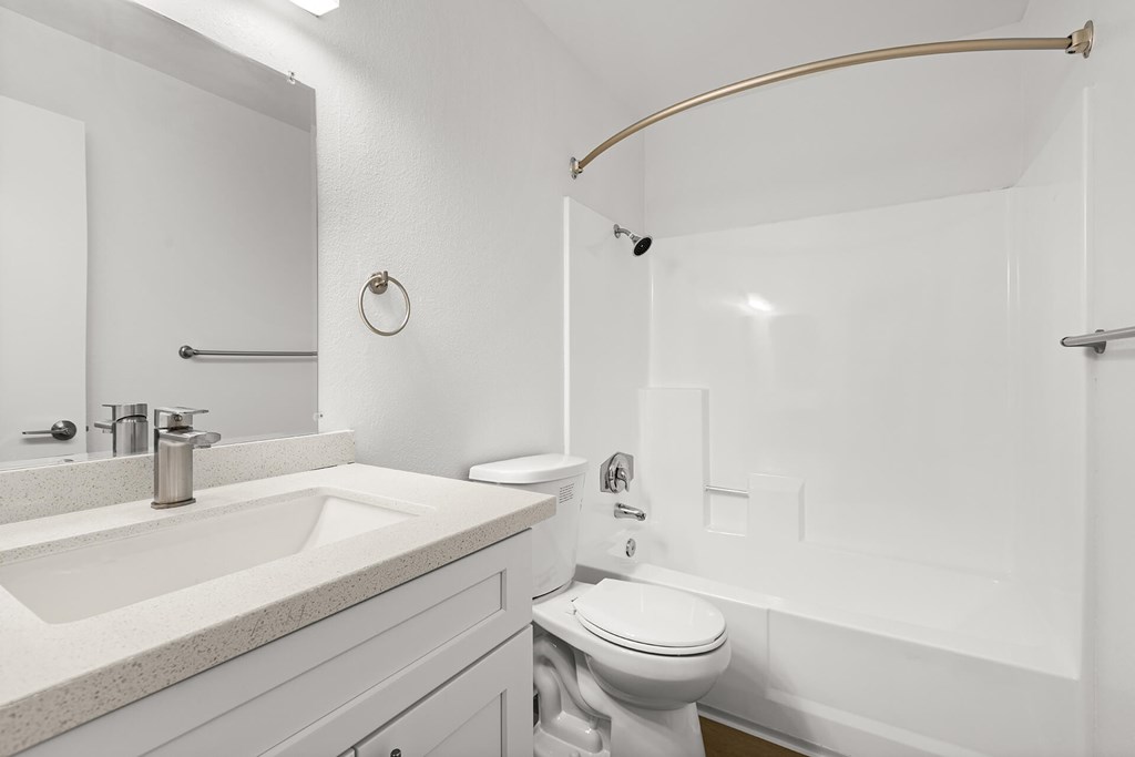 A white bathroom with a toilet, sink, and shower.