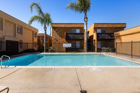 A swimming pool in front of a building with palm trees.