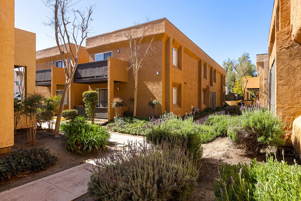A building with a yellow exterior and a garden in front.