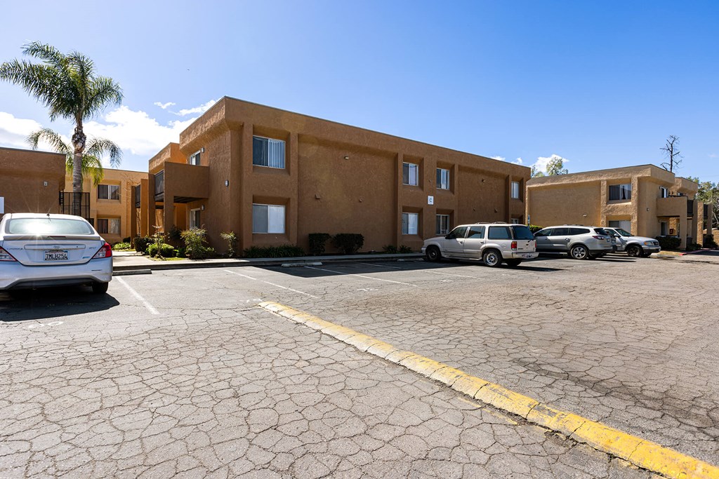 A parking lot with a building in the background and a car parked in the lot.