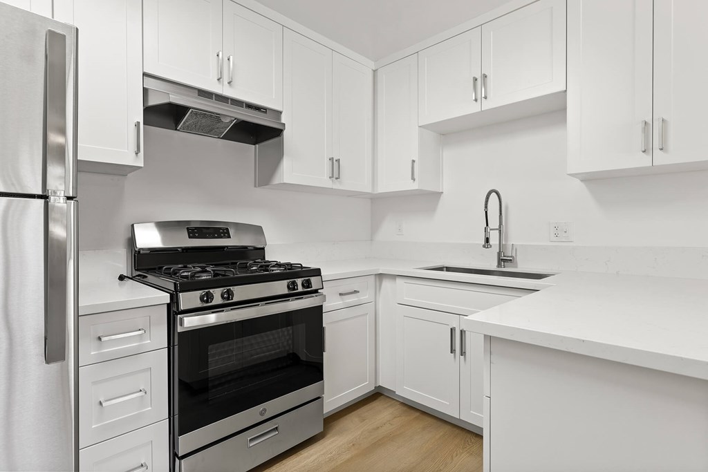 A modern kitchen with white cabinets and stainless steel appliances.