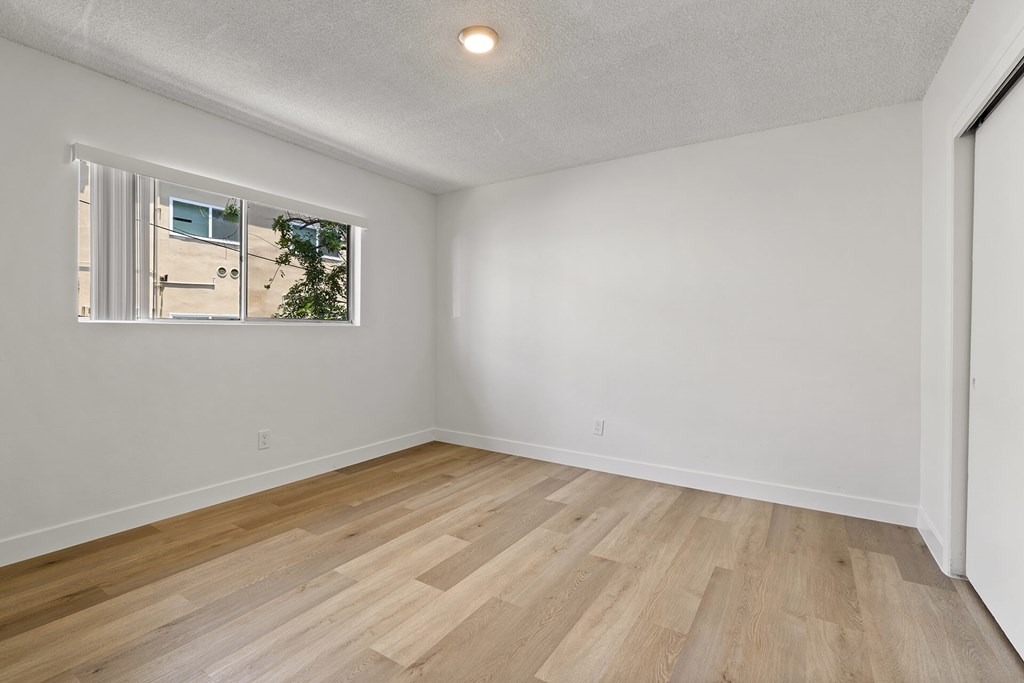 A room with a window and wooden flooring.
