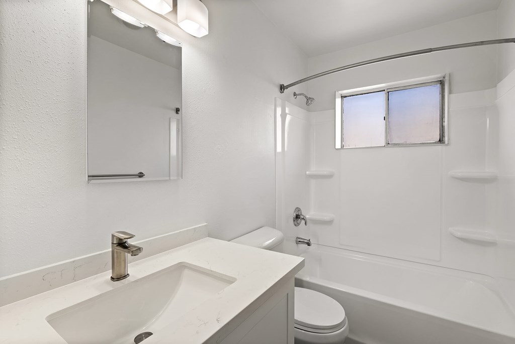 A white bathroom with a sink, toilet, and bathtub.