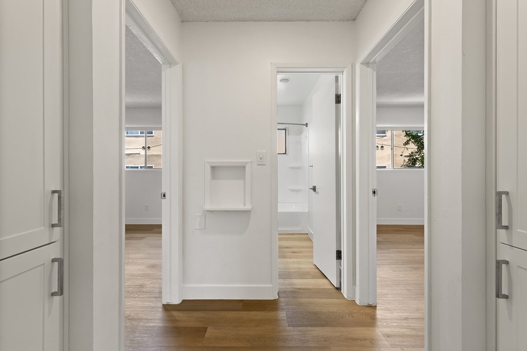 A white hallway with wood floors and white walls.