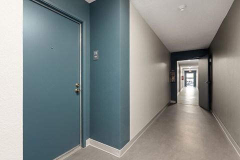 A hallway with a blue door and a white door at the end.