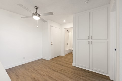A room with a ceiling fan and wooden flooring.