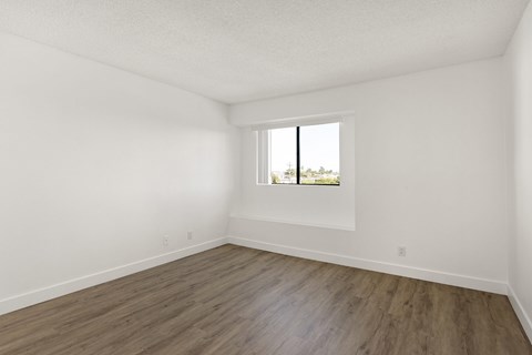 A room with a window and wooden flooring.