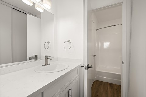 A white bathroom with a sink and mirror.