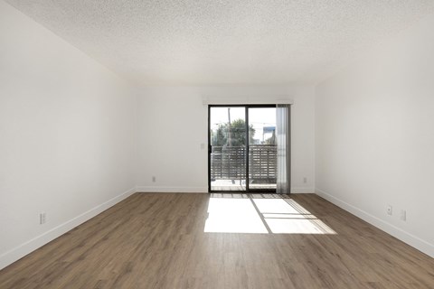 A room with wooden flooring and a sliding glass door.