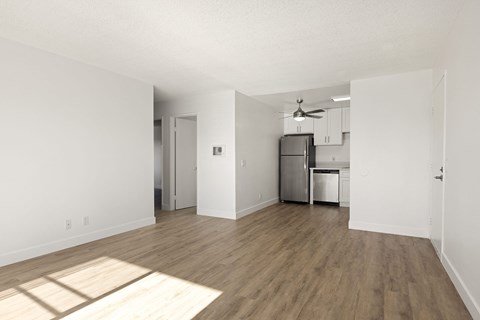 A kitchen with a refrigerator, sink, and cabinets is visible through a doorway.