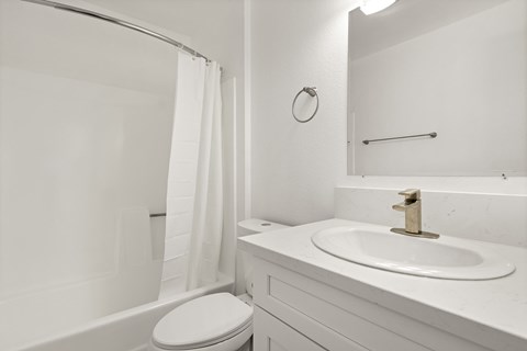 A white bathroom with a toilet, sink, and shower.