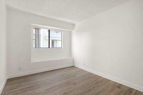 A room with a window and wooden flooring.