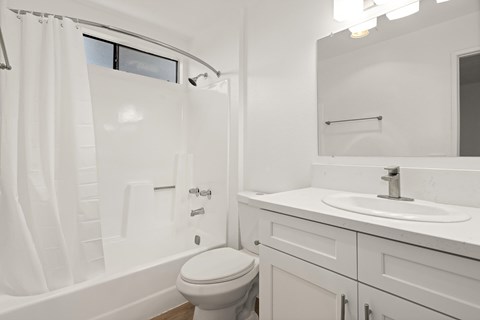 A white bathroom with a toilet, sink, and bathtub.