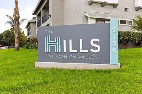 A sign for The Hills at Fashion Valley is displayed in front of a building.