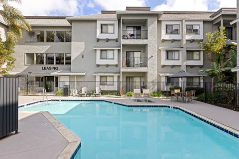 A swimming pool is in front of a multi-story apartment building.