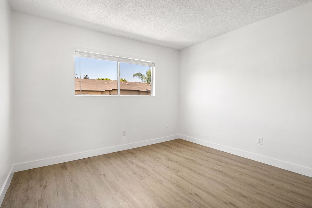 A room with a window showing a view of a building outside.