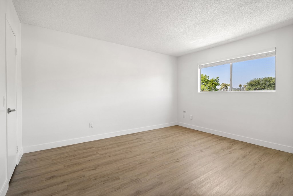Empty room with a window and wooden floor.