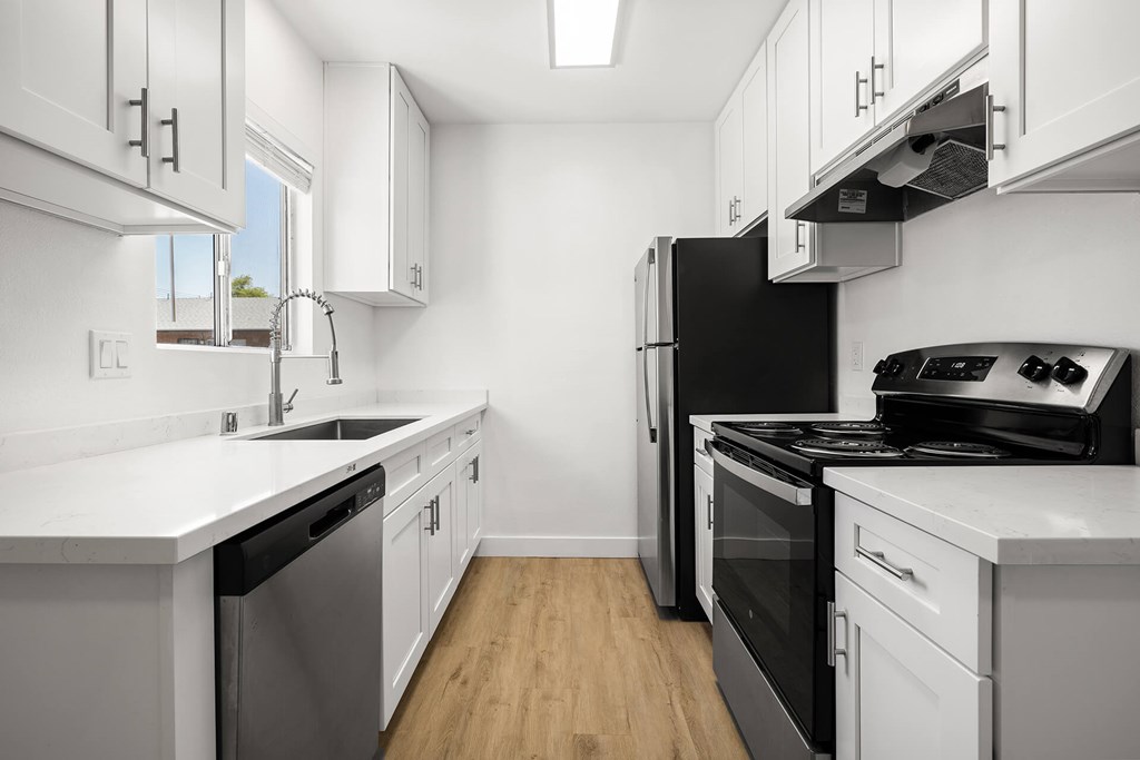 A modern kitchen with white cabinets and stainless steel appliances.