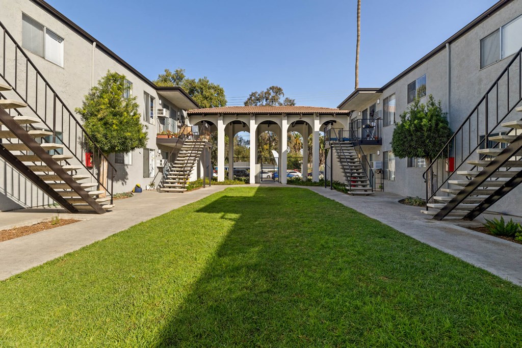 A courtyard with a grassy area and a building on either side.
