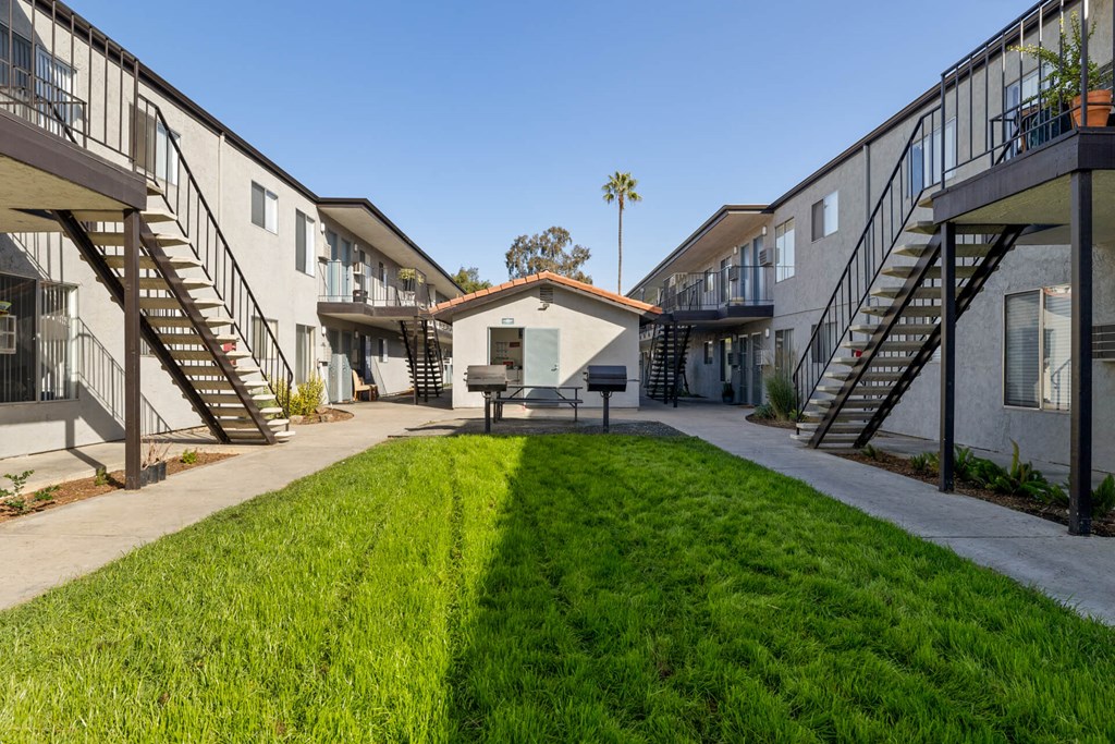 A sunny day at a residential complex with a green lawn in the foreground.