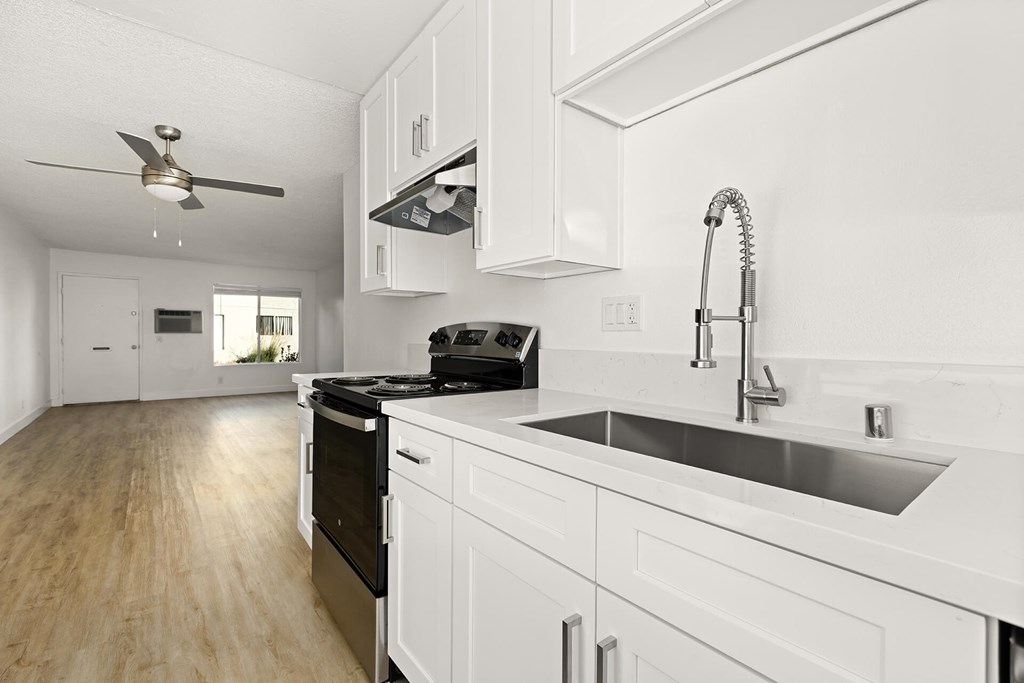 A modern kitchen with white cabinets and a black stove top oven.