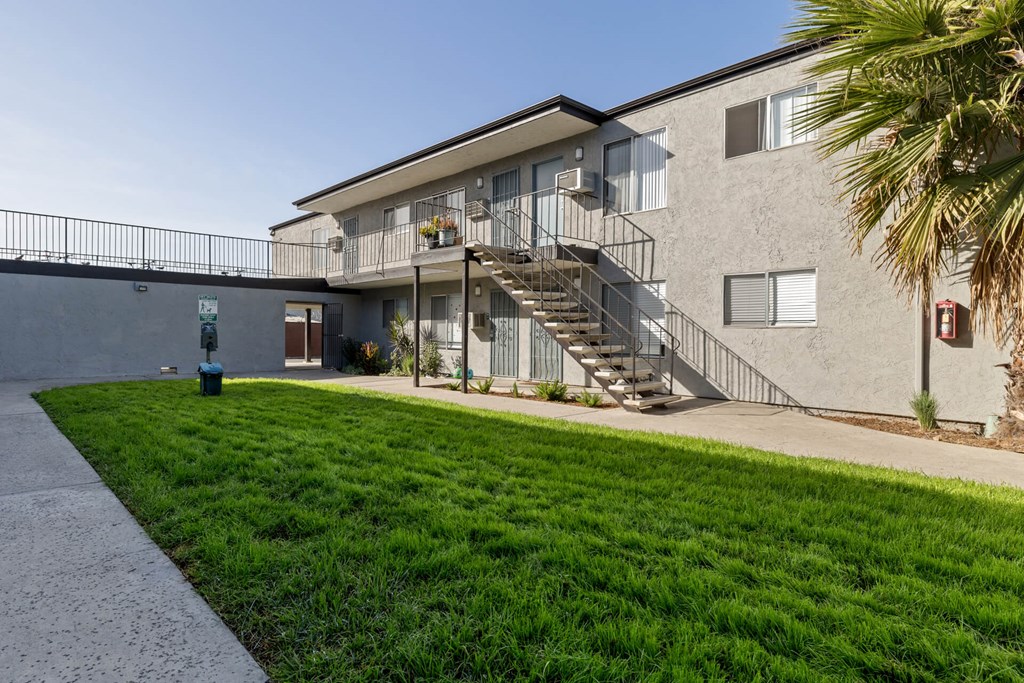 A building with a staircase and a green lawn in front.