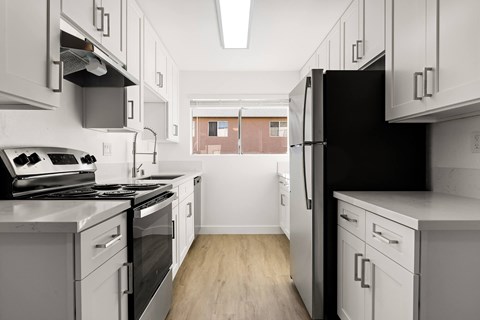A kitchen with white cabinets and a black refrigerator.