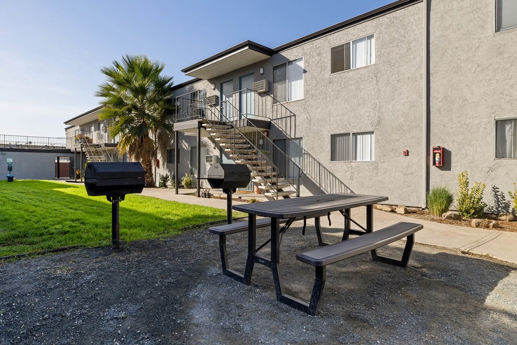 A picnic table is in front of a building with a palm tree.