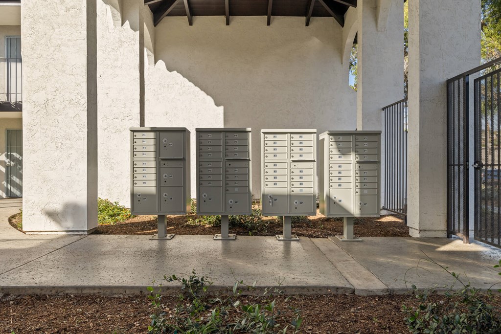 A row of mailboxes are lined up on a sidewalk.