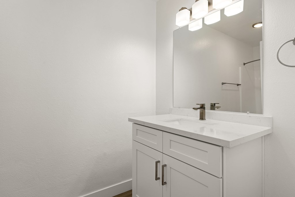 A white bathroom vanity with a sink and mirror.