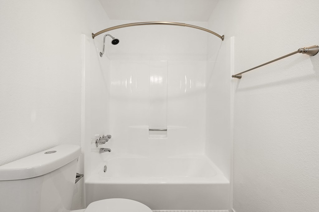 A white bathroom with a tub, toilet and sink.