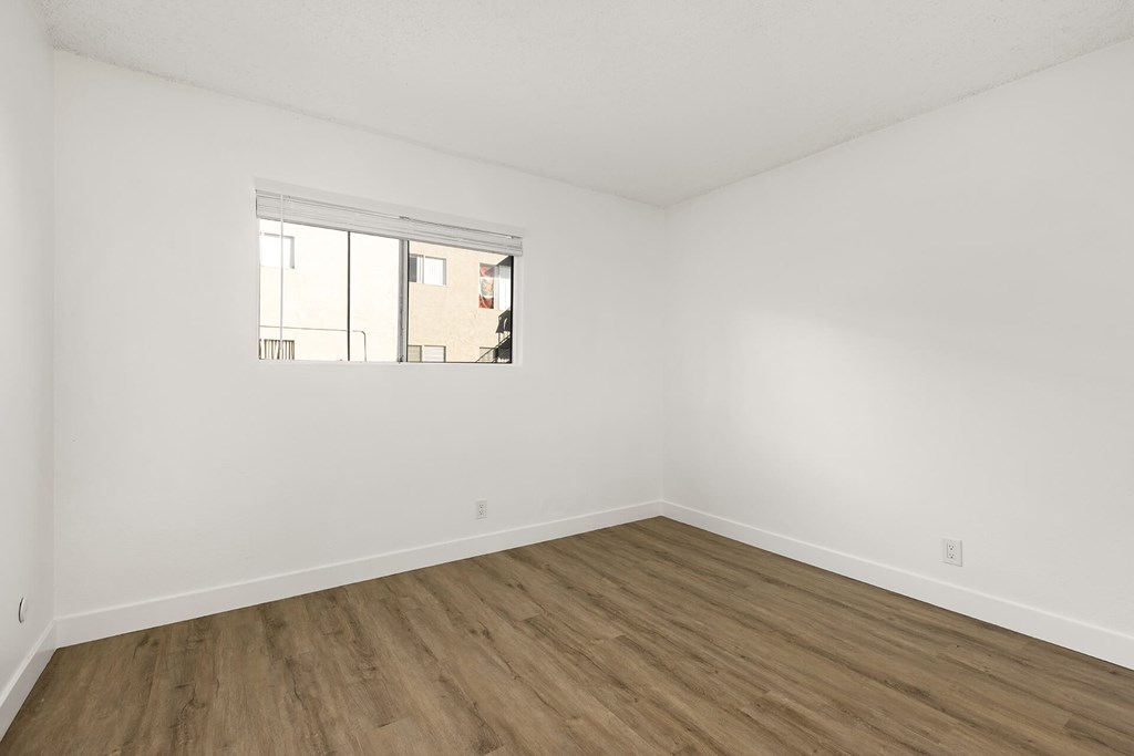 Empty room with a window and wooden floor.