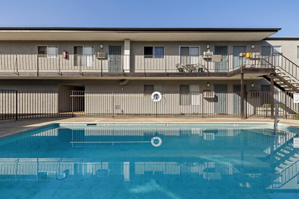 A pool in front of a building with a staircase on the right side.