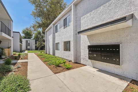 A white building with a black mailbox is on a sunny day.