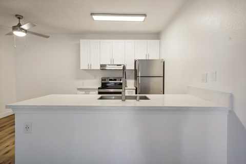 A kitchen with a stainless steel refrigerator and a white countertop.