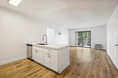 A kitchen with white cabinets and a wooden floor.