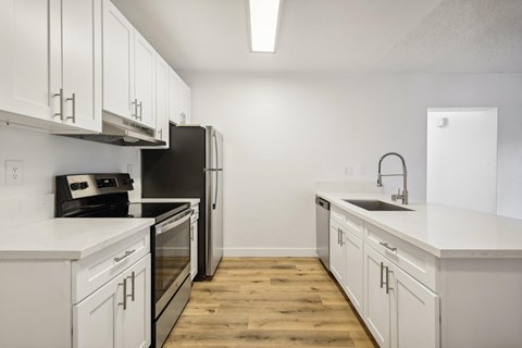 A kitchen with white cabinets and a black fridge.