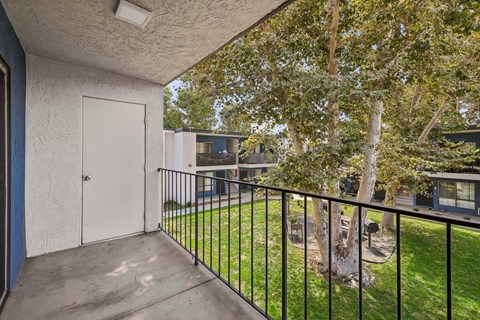 A balcony with a white door and a tree.