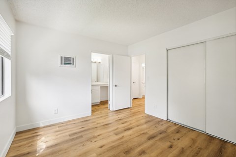 A white room with wood floors and a white door.