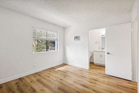 A room with wooden floors and a window with blinds.