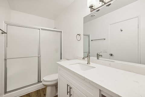 A white bathroom with a toilet, sink, and shower.