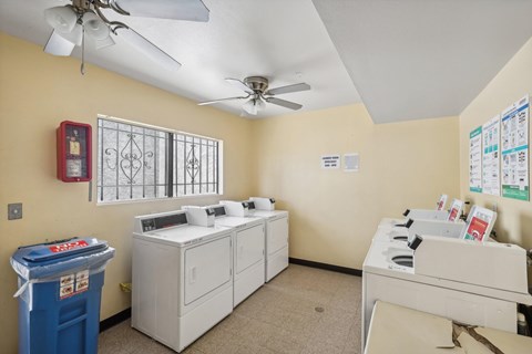 A room with a blue trash can, a window with bars, and a fan on the ceiling.