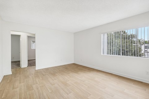 A room with wooden flooring and a window with blinds.