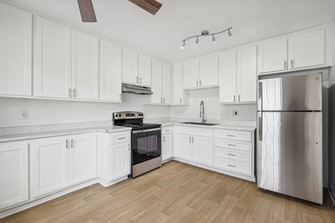 A kitchen with white cabinets and a stainless steel refrigerator.