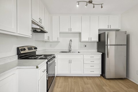 A modern kitchen with white cabinets and stainless steel appliances.