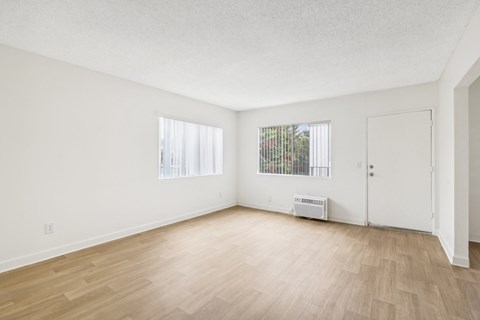 A room with a white ceiling, a window with blinds, a door, and a wooden floor.