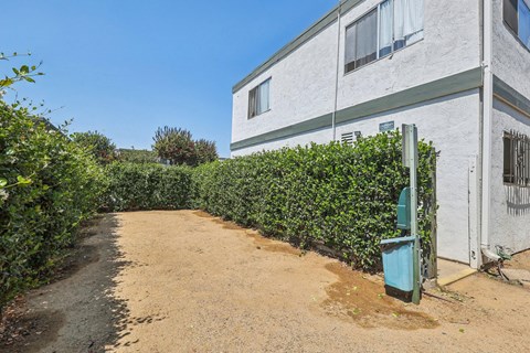 A white building with a green trash can in front of it.