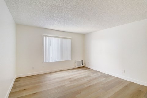 A room with wooden flooring and a window with blinds.
